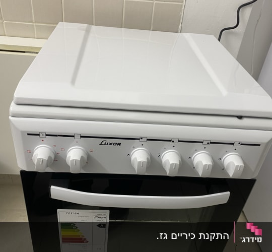 תנור לבן עם כפתורים ומדבקת דירוג אנרגיה